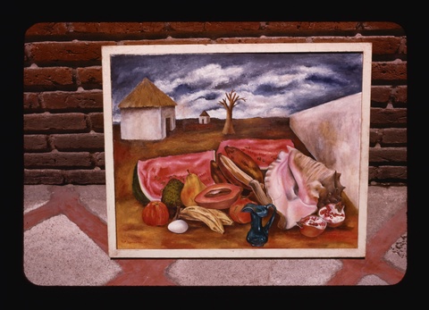 A photograph of a painting on a red and gray tiled floor, leaning against a red brick wall. The painting shows a large conch shell and a pile of lush, ripe fruit piled on the red dust of a dead landscape, next to a white wall that extends to the horizon. The fruit includes watermelon slices, an open pomegranate, a cut papaya, a pear, and several bananas.