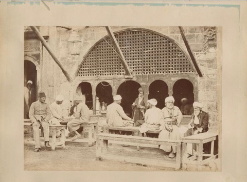 Traditional cafe in Cairo in the 19th century, showing nargiles, coffees being served, varying ages and dresses of customers (e.g. old people on far right, high class government official on the left). 