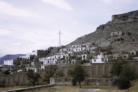 A color photograph of a village built on Koh-e Asmai mountain, taken from below.