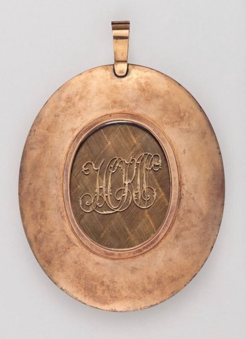 Brown, oval locket that features a woven hairwork in the middle with initials "HKW."