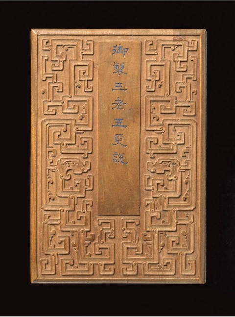 A wooden cover of an album that is decorated with a geometric pattern. A column in the center includes Chinese characters. 
