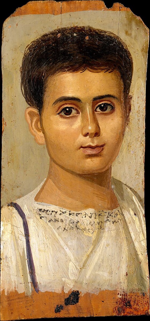 A lifelike portrait of a young boy in a white tunic with a Greek inscription across the chest listing his name and lineage. The inscription reads, “Eutyches, freedman of Kasanios,” and either “Son of Herakleides Evandros” or “Herakleides, son of Evandros.”