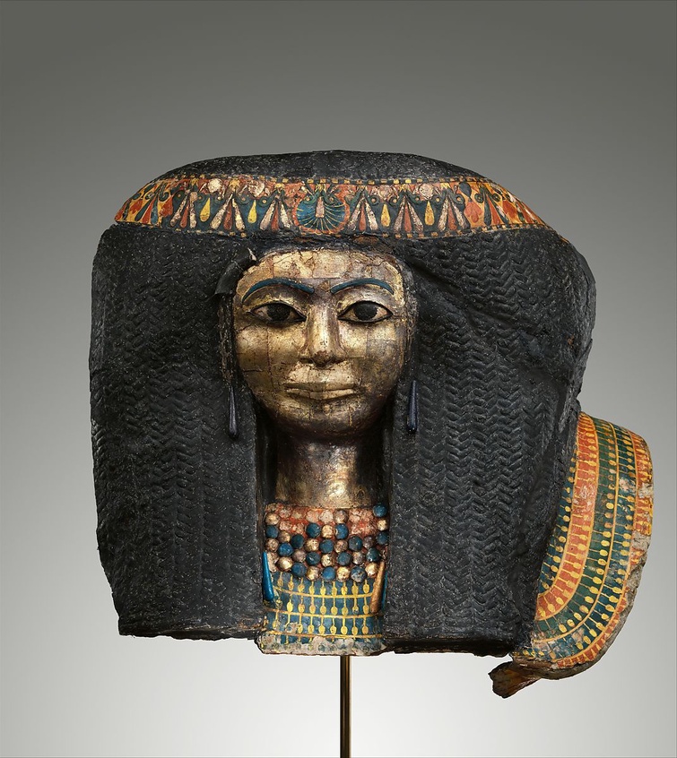 A New Kingdom funerary mask of a woman. She wears a braided wig, painted headband, and beaded necklaces and pendants.