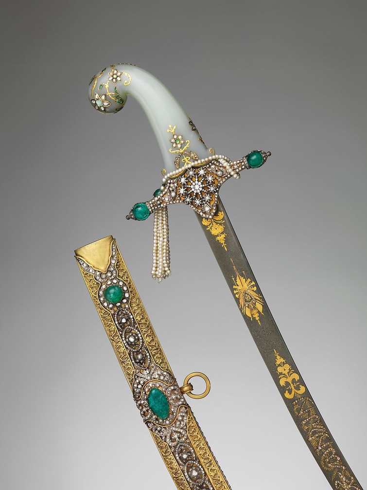 An Indian and Turkish saber with scabbard. The jade hilt and gold sheath are encrusted with diamonds, emeralds, pearls, and gemstones set in gilt-brass mounts. The blade is inscribed with arabesque and floral motifs in gold and has inlaid diamonds. 
