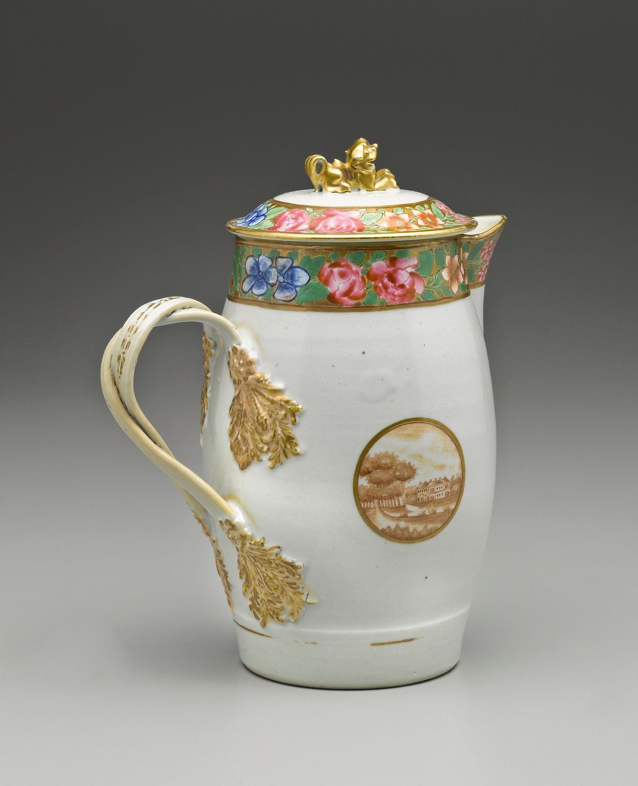 A white porcelain jug with a handle and lid. The jug features a landscape on the side and a floral motif around the top of the jug, and a sculpture of a crouching dog on top of the lid.