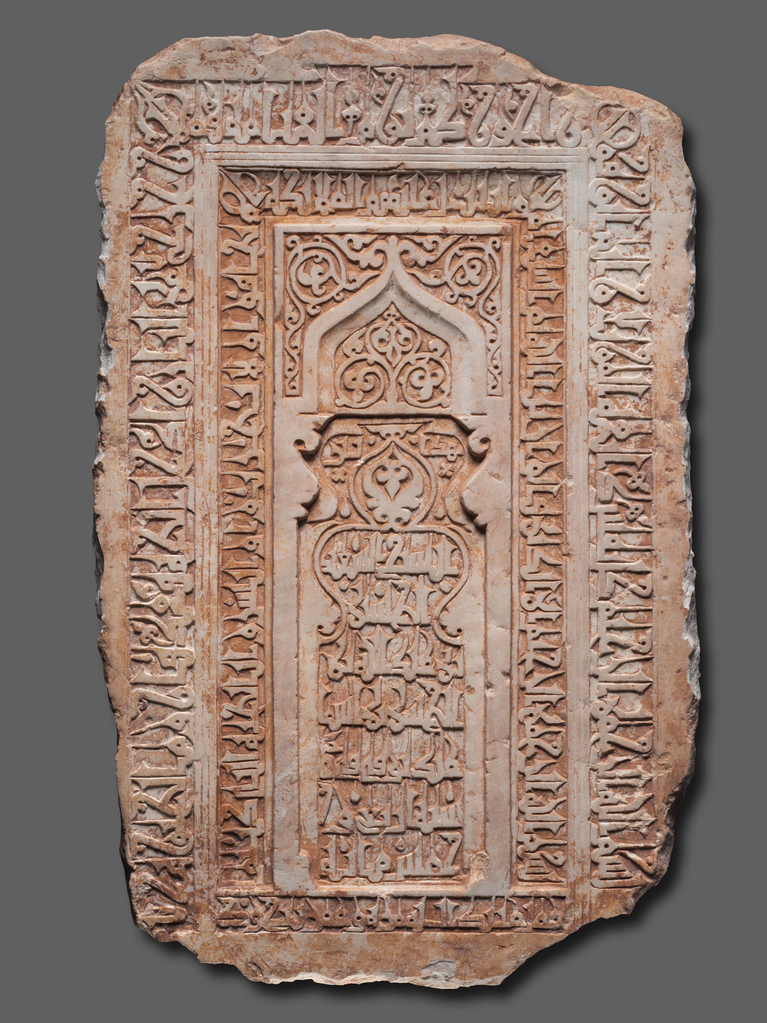 A 12th century fragment of Shaikh al-Husain ibn Abdallah ibn al-Hasan's tombstone, inscribed in Arabic Kufic calligraphy. The center is carved to resemble a mihrab with arabesque designs surrounding it.