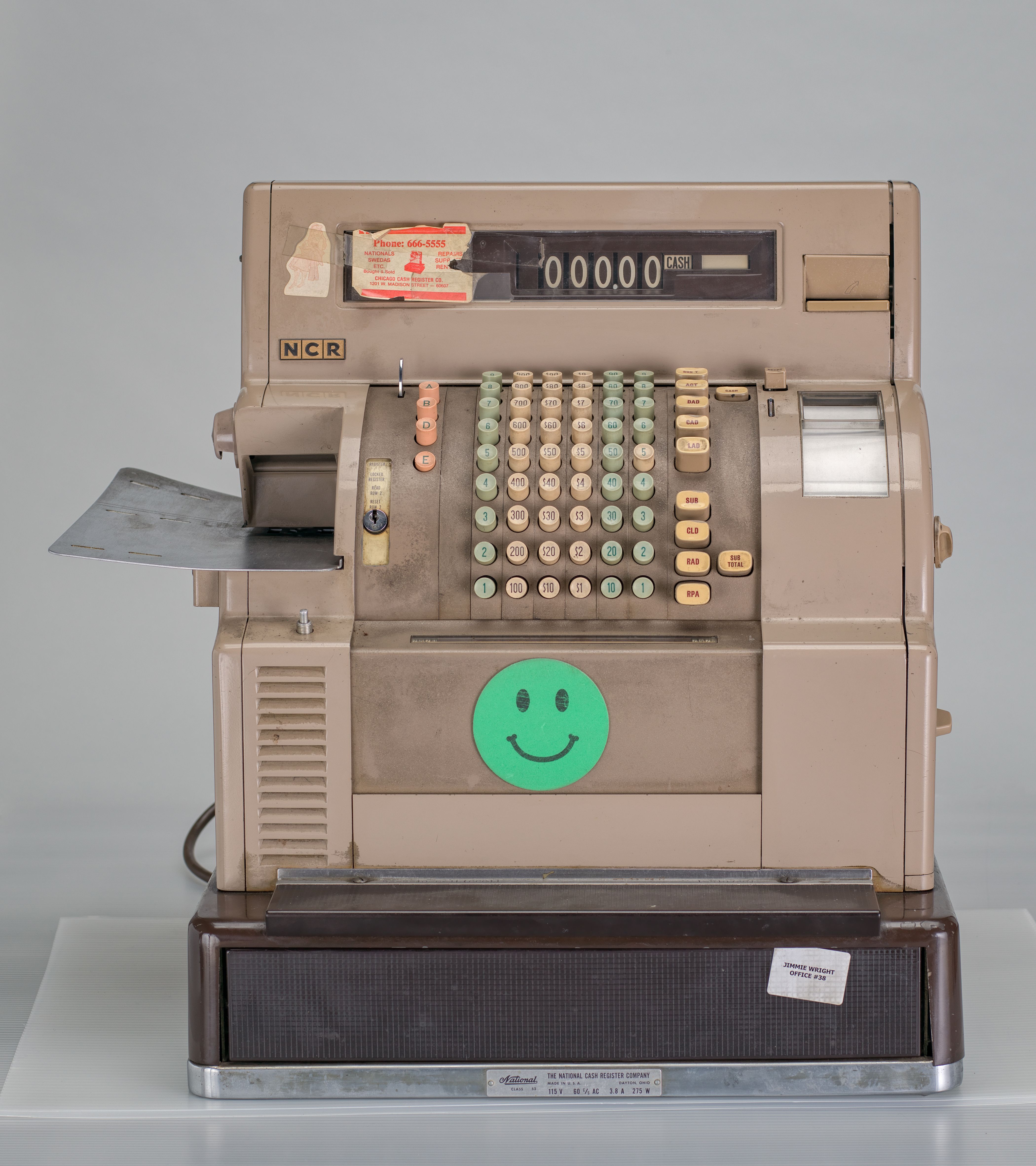 light brown cash register with a green smiley face on it